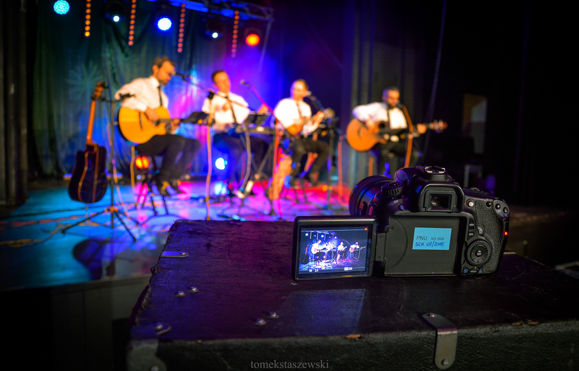 Na scenie SCK czterech muzyków z zespołu ALbo i Nie. Na pierwszym planie aparat fotograficzny.