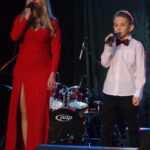 Daria Wantuła w długiej, czerwonej sukni oraz Szymon Wantuła z mikrofonami w rękach na scenie SCK- Bytków