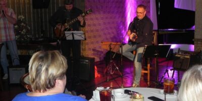Zdjęcie przedstawia Eugeniusza Szwarcera grającego na gitarze w towarzystwie zespołu