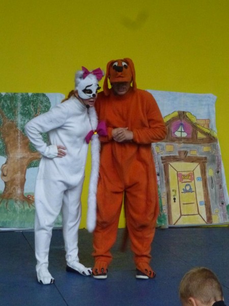Aktorzy przebrani za kotkę i psa grają na scenie w spektaklu dla dzieci
