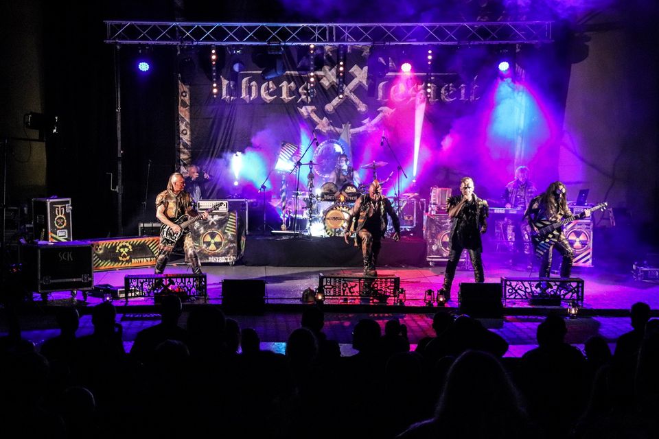 Na zdjęciu widok ogólny amfiteatru podczas koncertu Rock Noc. Widać scenę z kolorowymi światłami, na niej zespół oraz ciemne sylwetki fanów. Foto Monika Bilska