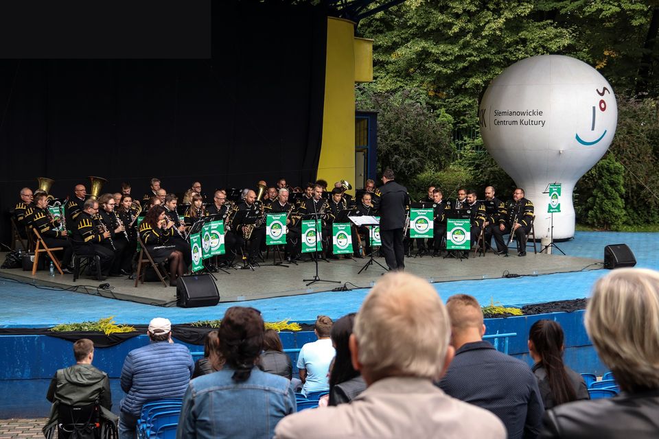 Na zdjęciu widok ogólny na scenę amfiteatru, na której znajduje się Górnicza Orkiestra Dęta z Bytomia. Na zdjęciu widać też część widowni.