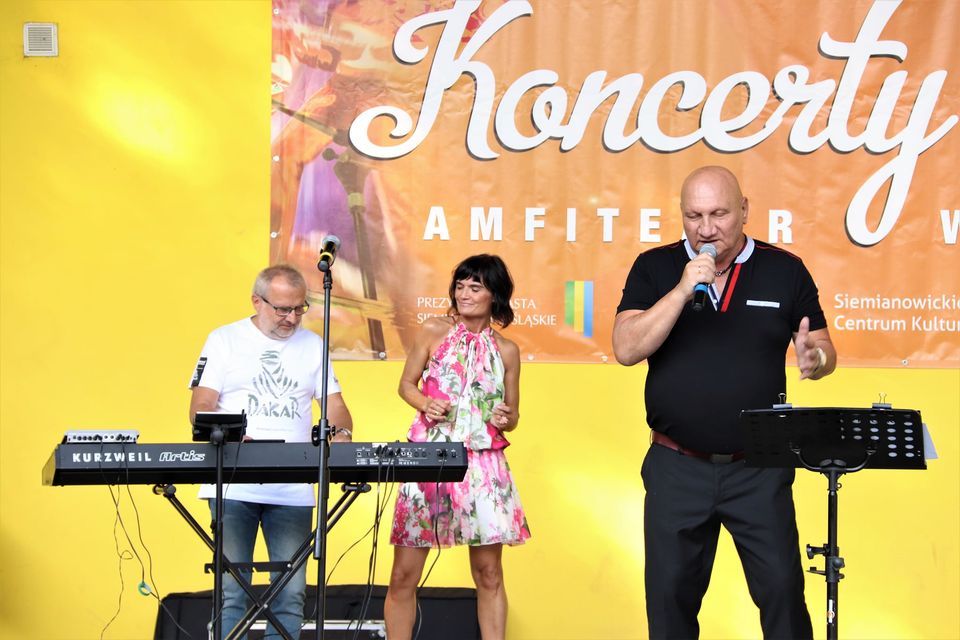 Widok na scenę, na któej znajdują się Piotr Herdzina i dwoje członków jego zespołu - wokalistka w biało-różowej sukience oraz klawiszowiec. Foto Monika Bilska