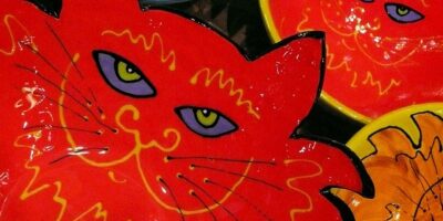 Zdjęcie przedstawia kolorowe naczynia ceramiczne z wizerunkami kotów.