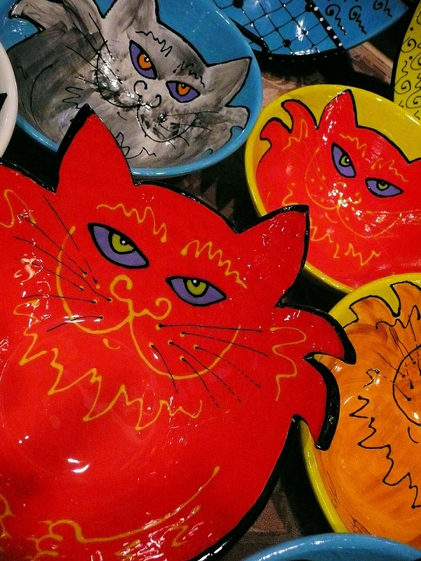 Zdjęcie przedstawia kolorowe naczynia ceramiczne z wizerunkami kotów.