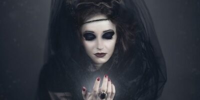 Zdjęcie przedstawia postać kobiety ucharakteryzowaną na czarownicę.