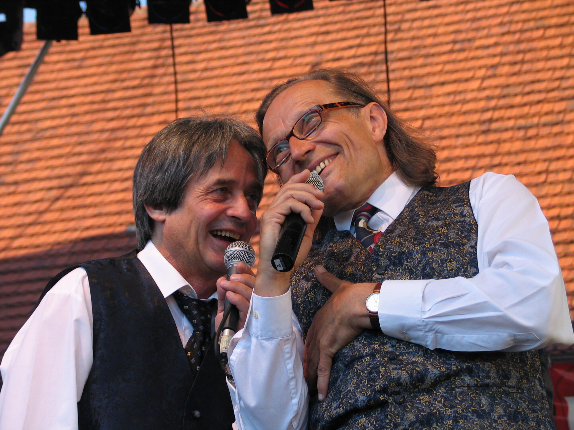 Zdjęcie przedstawia uśmiechniętych Ecika i Masztalskiego podczas występu przed publicznością
