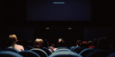 Ciemna sala kinowa pełna foteli oraz odwiedzających