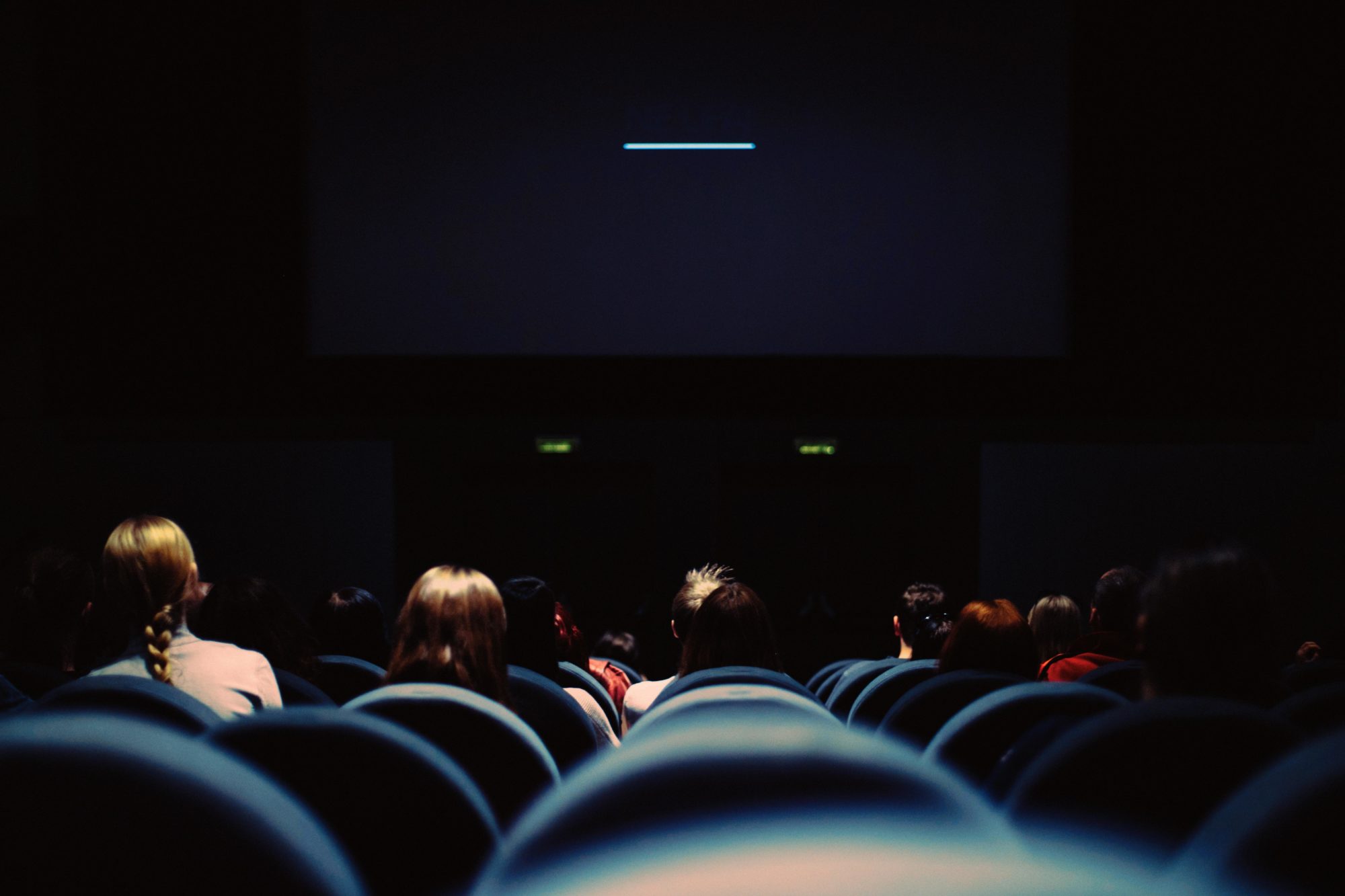 Ciemna sala kinowa pełna foteli oraz odwiedzających
