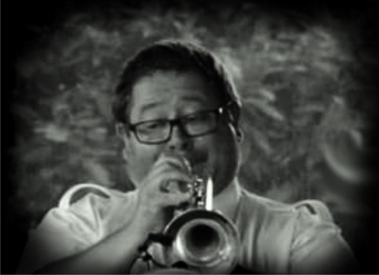 Czarno-białe zdjęcie przedstawiające muzyka Krzysztofa Roga grajacego na trąbce