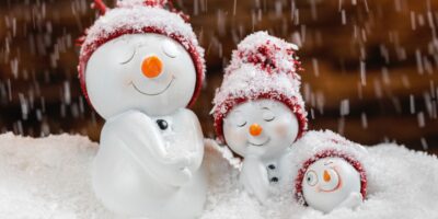 trzy bałwanki w czapkach stojące na śniegu
